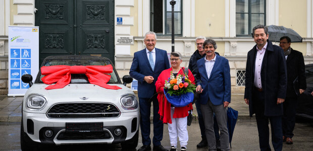 Eine große Freude war es für den Innenminister, den Hauptpreis des Verkehrssicherheitsgewinnspiels 2021 an den Gewinner aus Nordrhein-Westfalen zu übergeben. - © Sebastian Widmann / StMI Innenminister Joachim Herrmann mit Gewinnern neben BMW Mini mit Schleife