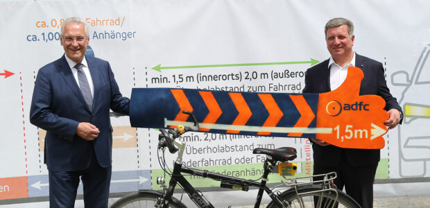 13. Juli 2022: Mehr Sicherheit für Fahrradfahrer: Innenminister Joachim Herrmann setzt sich gemeinsam mit Verkehrsminister Christian Bernreiter, ADFC und ADAC für mehr Sicherheit beim Radfahren ein. Autofahrer sollen dafür sensibilisiert werden, die Abstandsregeln beim Überholen von Fahrradfahrern einzuhalten. „Wenn sich Autofahrer und Radfahrer gemeinsam an die Regeln halten, können viele und vor allem schwere Verkehrsunfälle verhindert werden“, so Herrmann. - © Sammy Minkoff Präsentation eines Banners, dass den Sicherheitsabstand von 1,5 Metern verdeutlicht