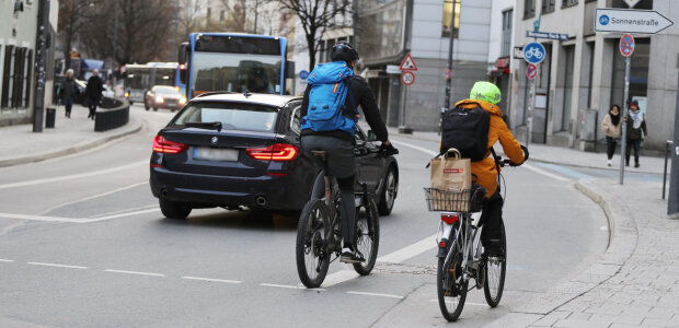 Auf dem Bild sind zwei Radfahrer von hinten zu sehen, die im Straßenverkehr in München unterwegs sind