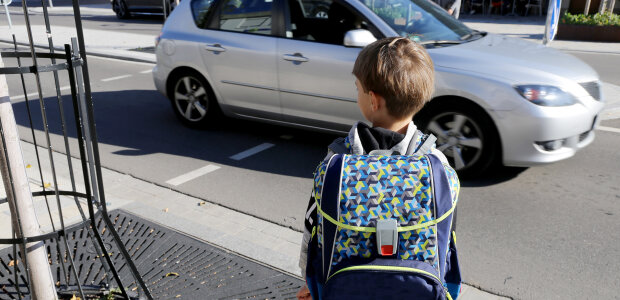 Schulkind von hinten vor der Überquerung einer Straße
